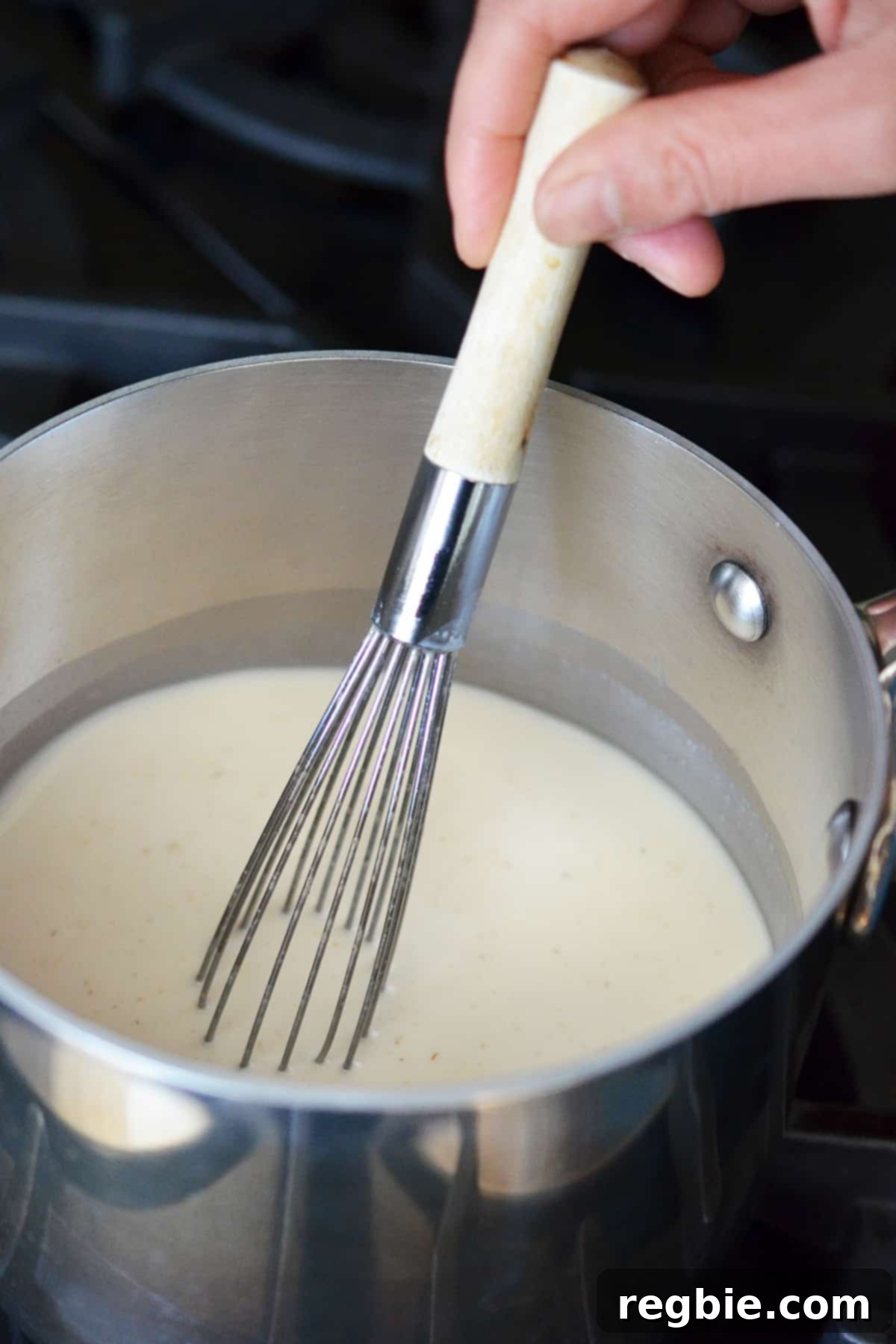 Whisking the Panna Cotta mixture in a small saucepan as it warms up.