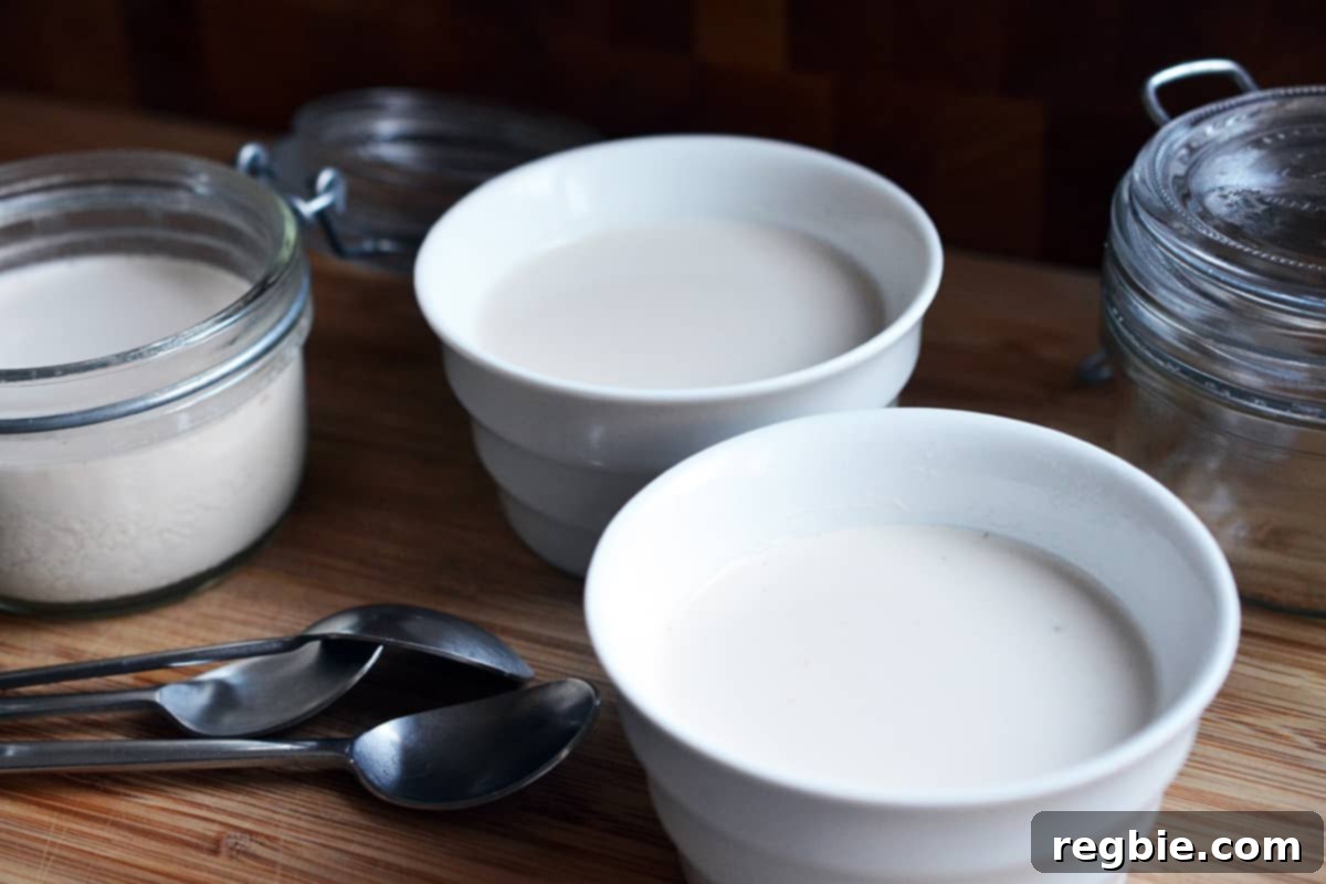 A side view of chilled Panna Cotta in white ramekins and in clear glass jars next to some teaspoons.