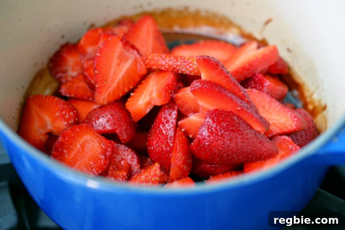 A closeup shot of sliced strawberries and balsamic vinegar in a blue saucepan.