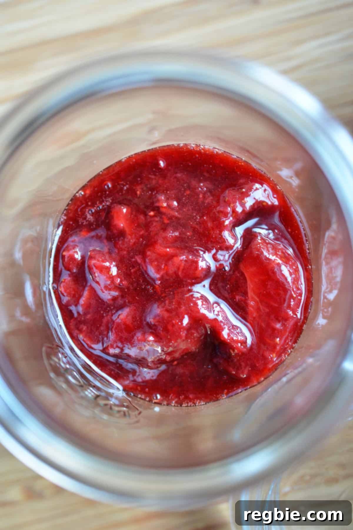 An overhead shot of a jar filled with strawberry balsamic compote, a topping for Panna Cotta.