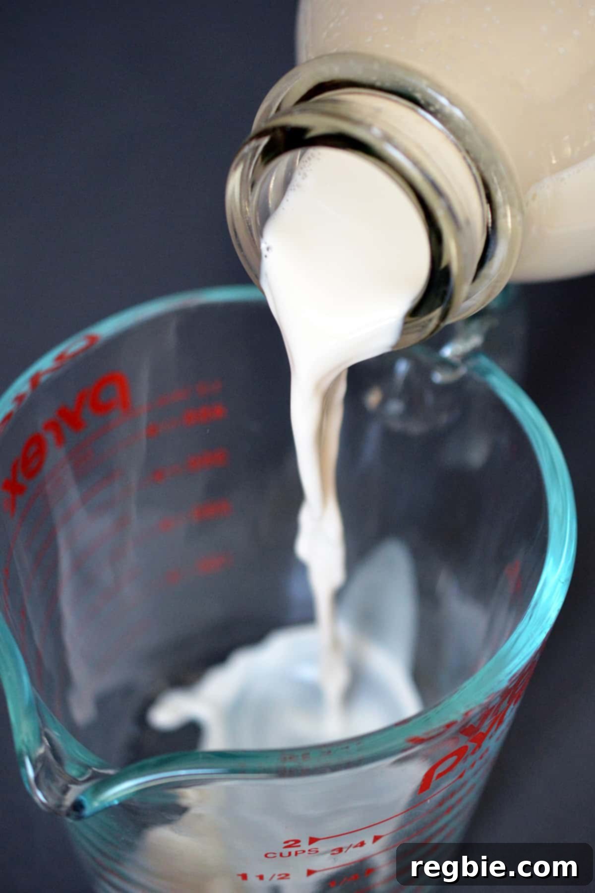 Pouring almond milk into a glass measuring cup.
