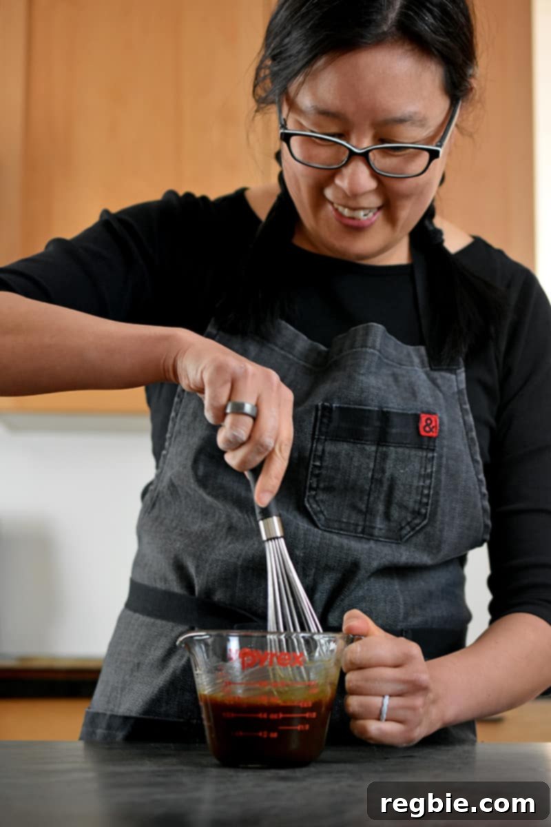 One-Pan Wonder Chicken Stir-Fry 6 A smiling Asian woman is whisking All-Purpose Stir-Fry Sauce with other seasonings in a 2 cup Pyrex measuring cup