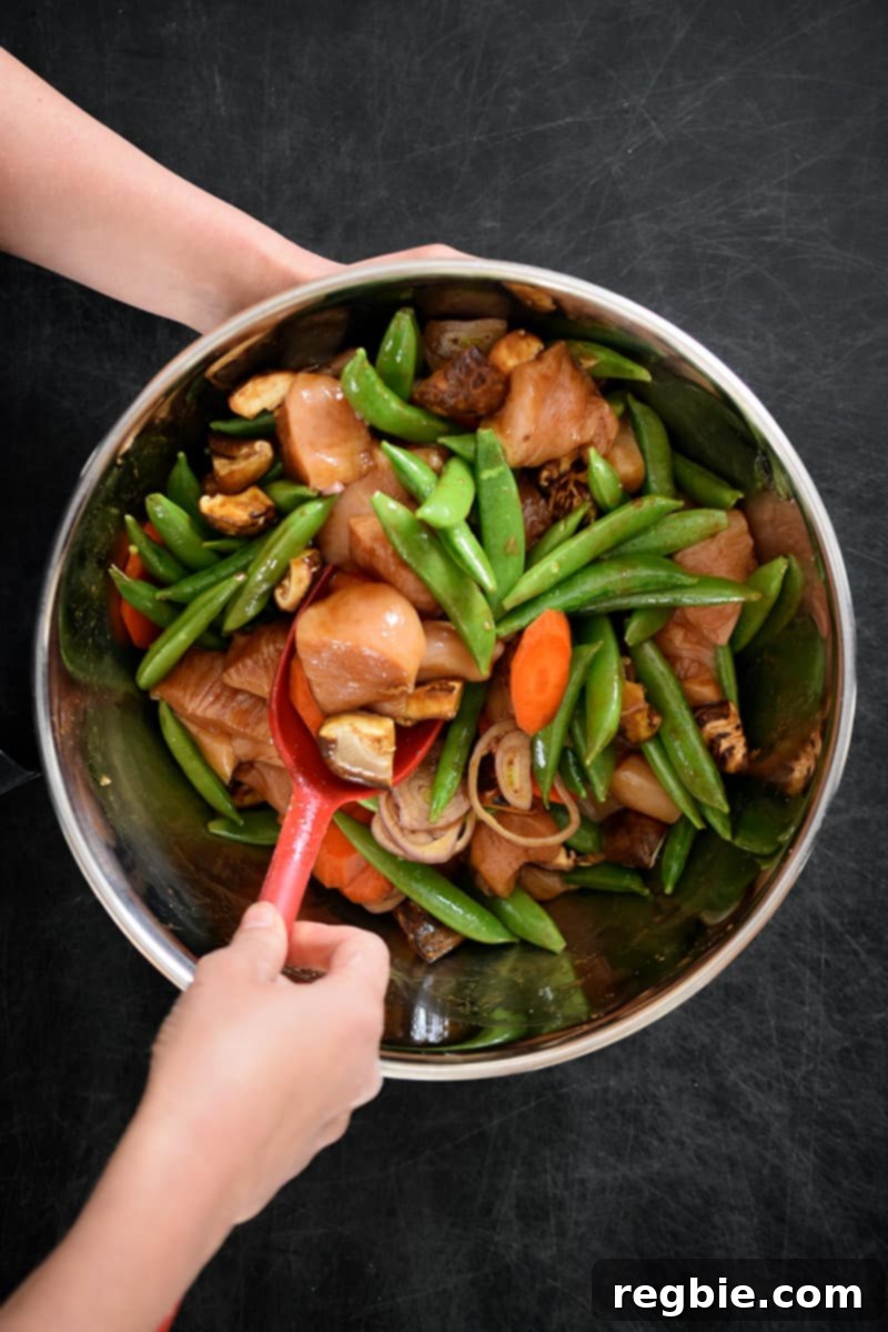 One-Pan Wonder Chicken Stir-Fry 8 An overhead shot of someone mixing vegetables and chicken with stir-fry sauce