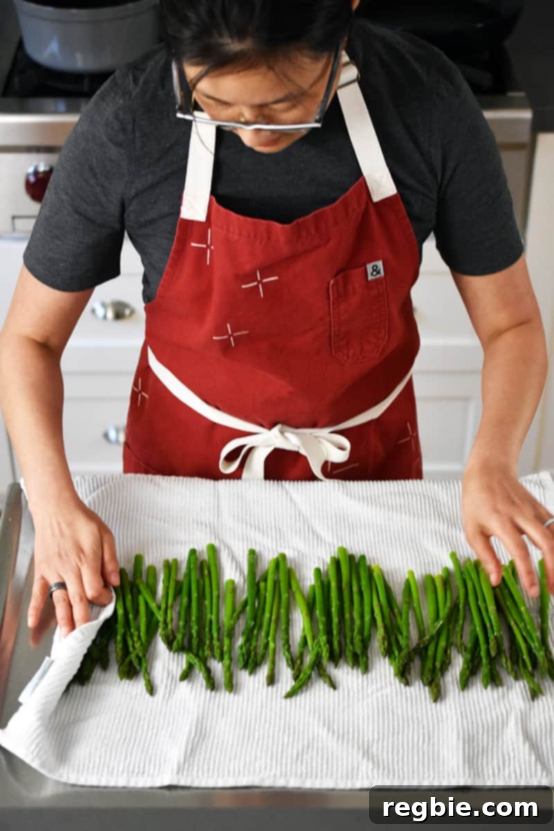 Whole30 Keto Paleo Asparagus Mimosa 13 Someone in a red apron has cooked asparagus on a large white kitchen towel.
