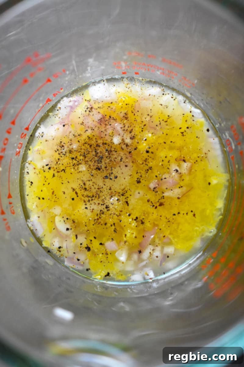 Whole30 Keto Paleo Asparagus Mimosa 14 An overhead shot closeup shot of a liquid measuring cup filled with minced shallots, lemon zest, lemon juice, champagne vinegar, salt, and pepper