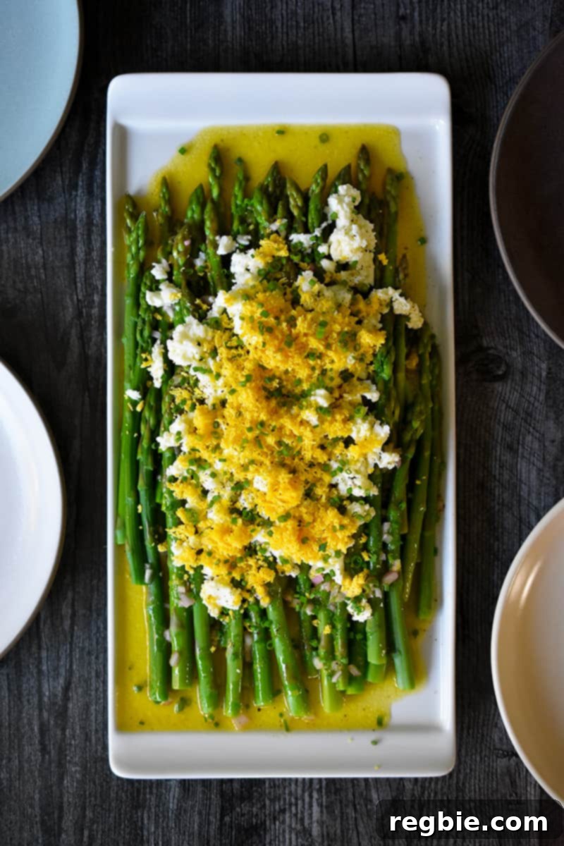 Whole30 Keto Paleo Asparagus Mimosa 20 An overhead shot of a rectangular plate filled with Asparagus Mimosa, cooked asparagus tossed with a lemon vinaigrette and topped with chopped hard boiled eggs and chives.