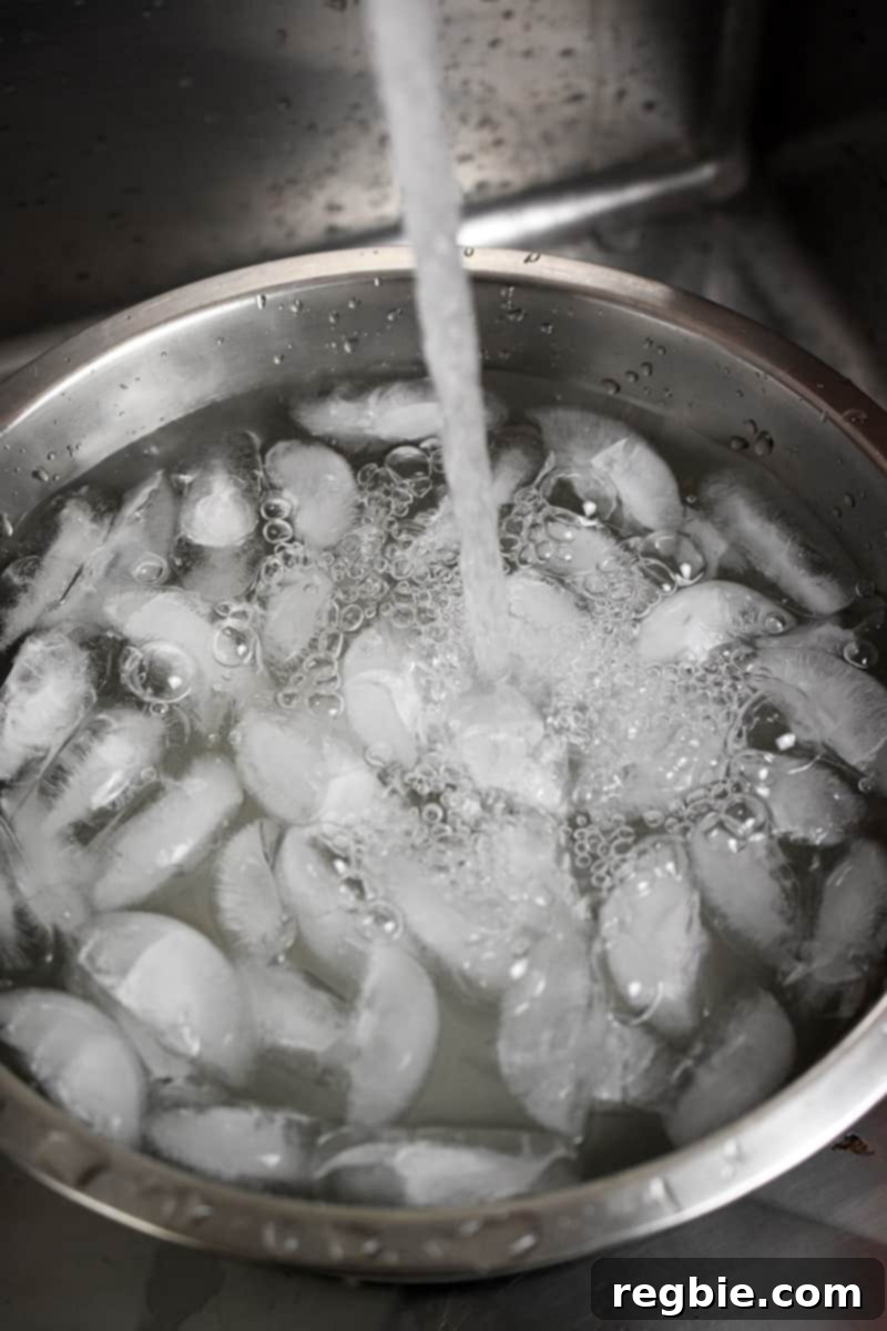 Whole30 Keto Paleo Asparagus Mimosa 6 A large silver bowl with ice is being filled with water.