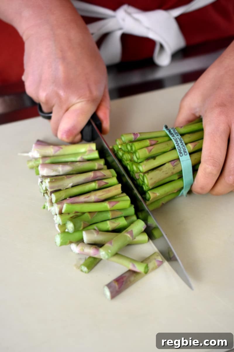 Whole30 Keto Paleo Asparagus Mimosa 7 An overhead shot of someone trimming the woody ends off of a bunch of asparagus.