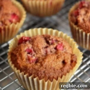 Close up shot of golden-brown paleo strawberry muffins resting on a metallic cooling rack, showcasing their rustic texture and inviting appearance.
