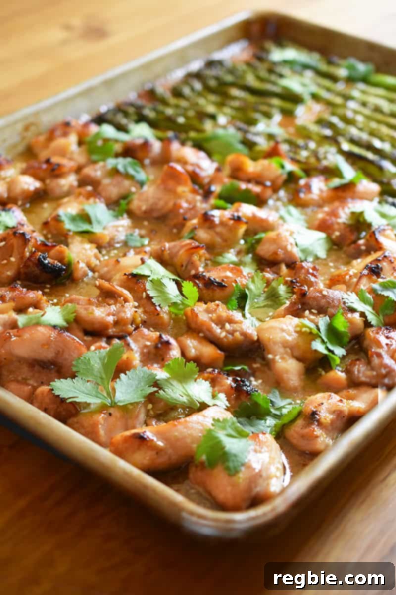 Simple Sheet Pan Chicken & Asparagus: Paleo Perfection 4 A enticing side view of perfectly cooked sheet pan chicken and asparagus, garnished with fresh cilantro and sesame seeds, presented on a rustic wooden tabletop.