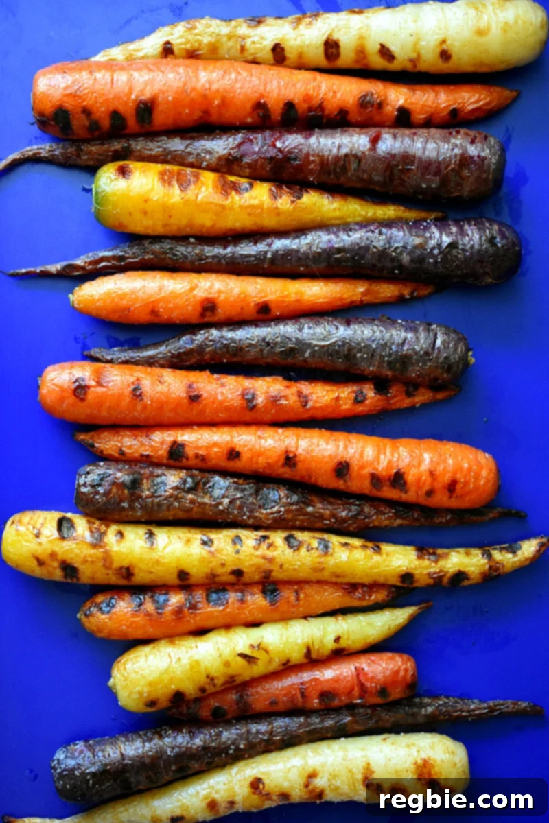 An overhead shot of a rimmed baking sheet topped with grilled rainbow colored carrots