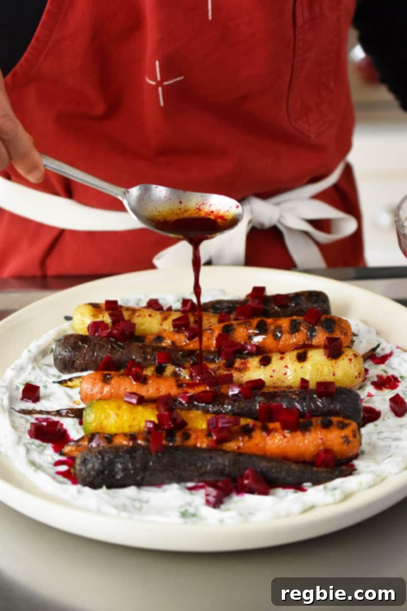 Someone in a red apron is adding beet vinaigrette on top of grilled carrots on coconut yogurt.