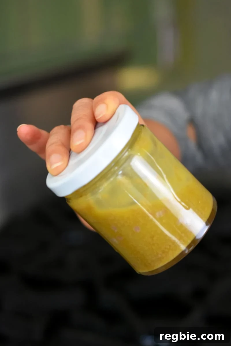 Irresistible Umami Avocado Salad with Garlic Anchovy Vinaigrette 11 A hand is shaking a closed jar filled with garlic anchovy vinaigrette.