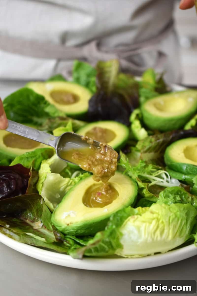 Irresistible Umami Avocado Salad with Garlic Anchovy Vinaigrette 15 Adding a spoonful of garlic anchovy vinaigrette into each halved avocado on the salad greens.