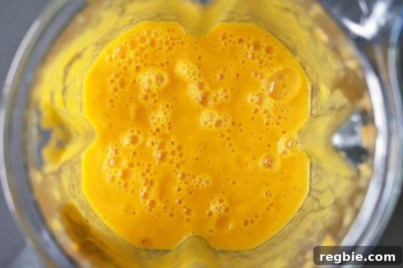 An overhead shot of pureed Carrot Cardamom Soup in a Vitamix blender.