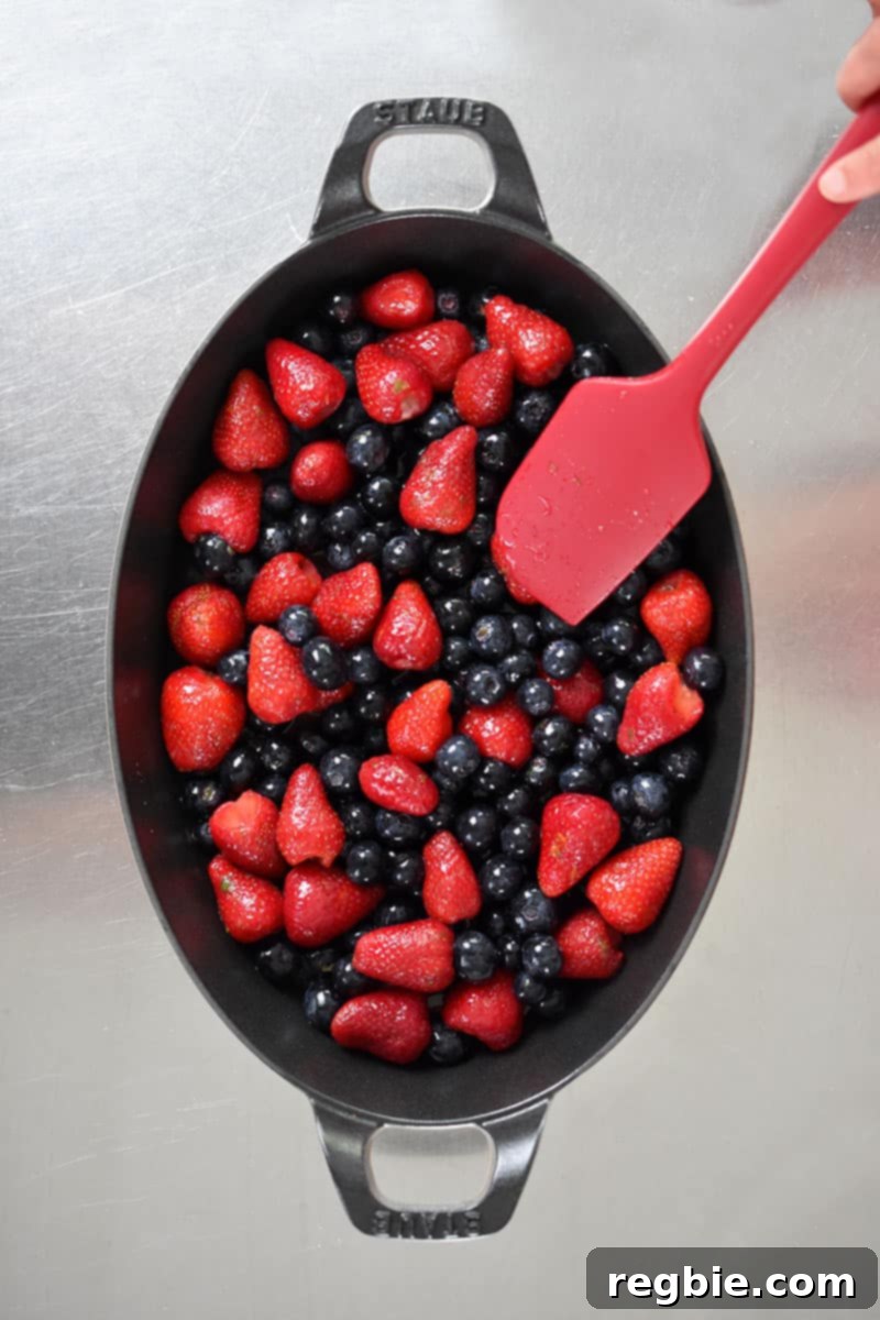 An overhead shot of an oval baking dish filled with berry crisp filling.