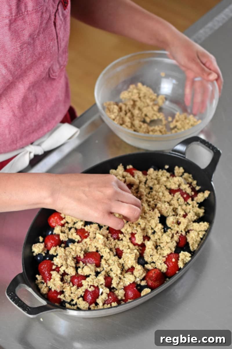 Adding the paleo, gluten-free, and vegan topping on a berry crisp.