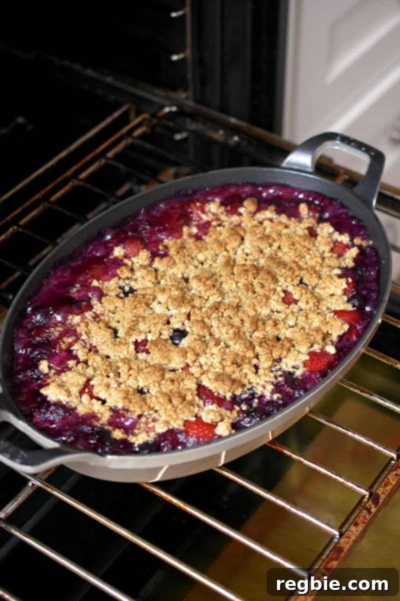 An open oven with a bubbling paleo berry crisp on the middle rack