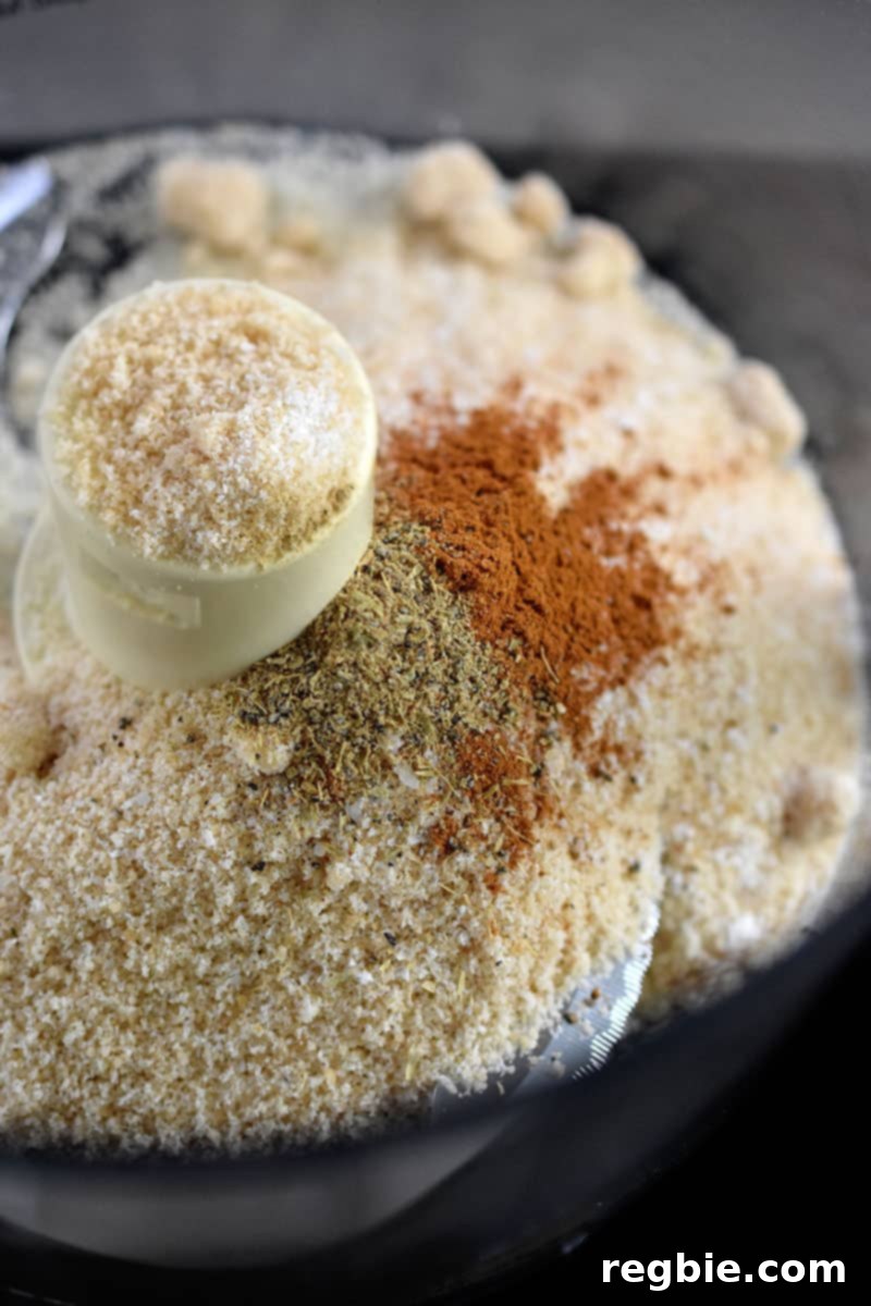 An overhead shot of an open food processor filled with the dry ingredients to make a paleo berry crisp