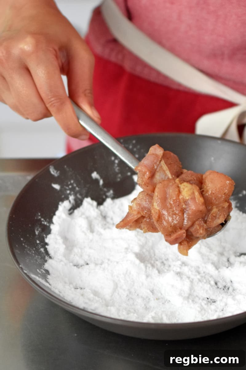 Coating the marinated chicken with potato starch before frying the Taiwanese popcorn chicken.