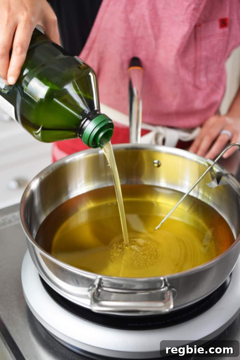 A person in a red apron is pouring avocado oil into a pot.