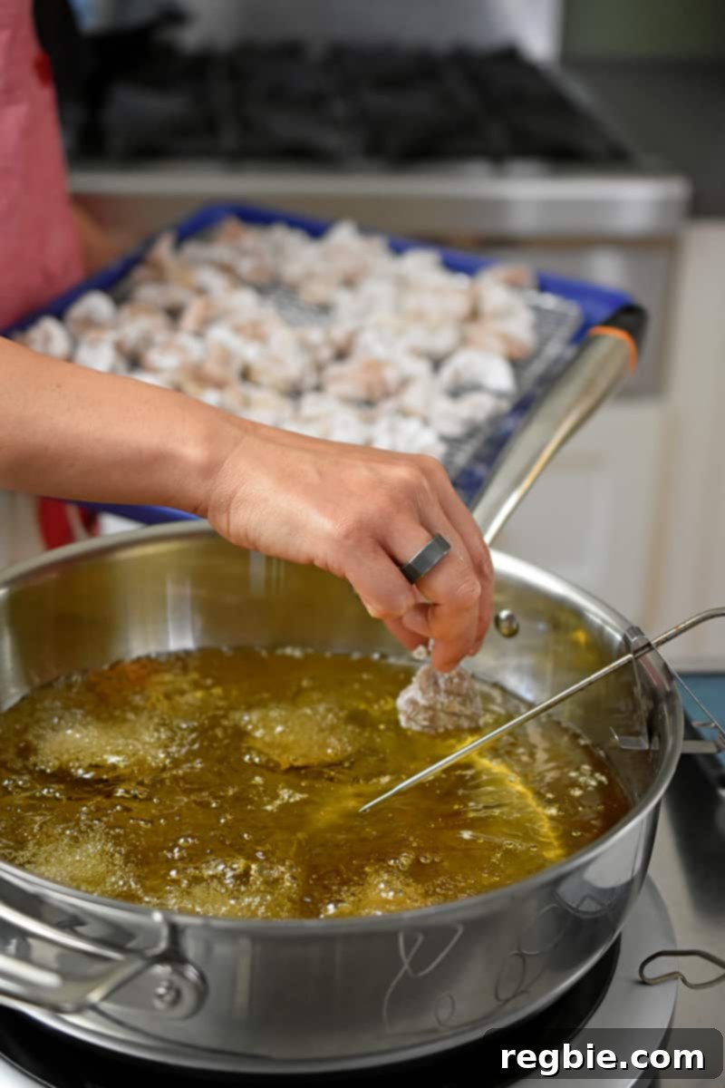 Adding battered chicken bites to hot oil to make Taiwanese popcorn chicken