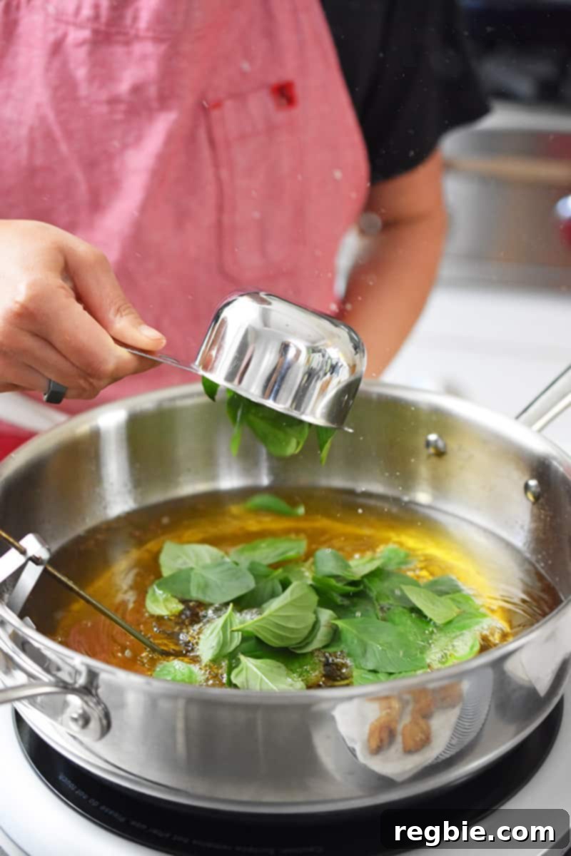 Adding Thai Basil to a pot filed with hot oil.