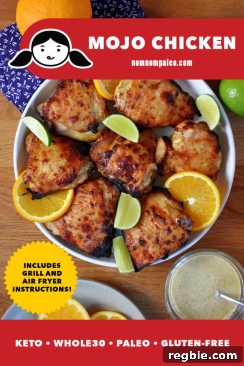 An overhead shot of a platter of paleo, keto, and whole30 Cuban-inspired Mojo Chicken on a round platter surrounded by sliced oranges and limes.