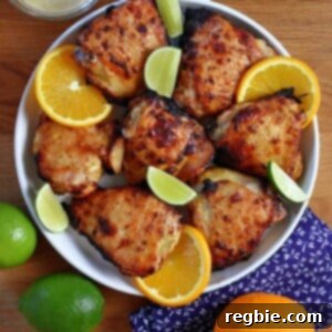An overhead shot of a round platter filled with mojo chicken, mojo marinade, and oranges and limes.