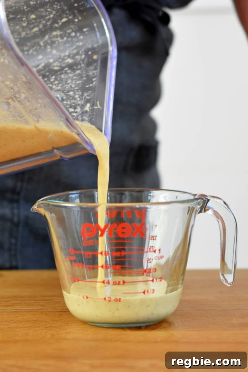 Pouring mojo sauce from a blender into a liquid measuring cup.