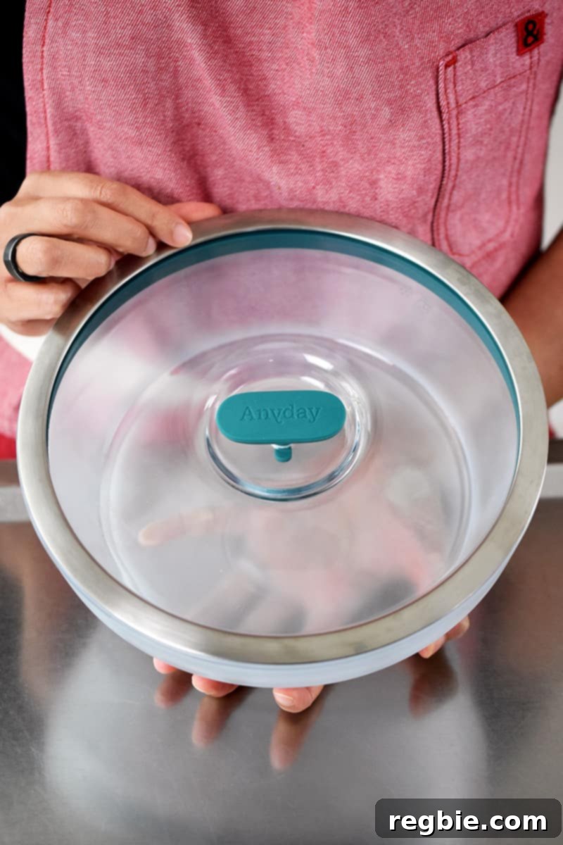 Master Crispy Microwave Bacon: Clean and Waste-Free 4 Someone in a red apron is holding a round Anyday microwave glass container.