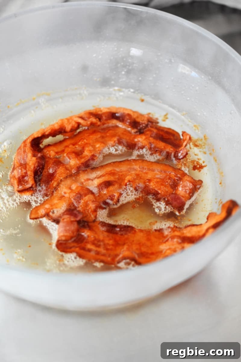 Master Crispy Microwave Bacon: Clean and Waste-Free 9 An overhead shot of a shallow glass container filled with crispy bacon and bacon drippings.