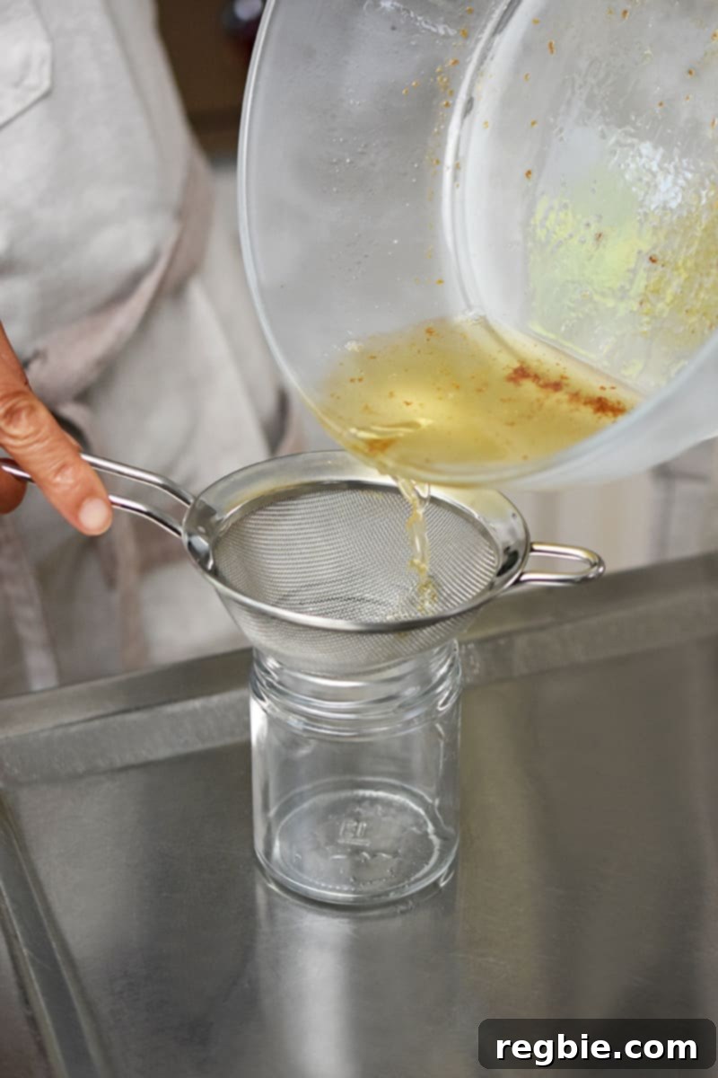 Master Crispy Microwave Bacon: Clean and Waste-Free 10 Pouring bacon drippings from a glass bowl to a jar with a fine mesh sieve