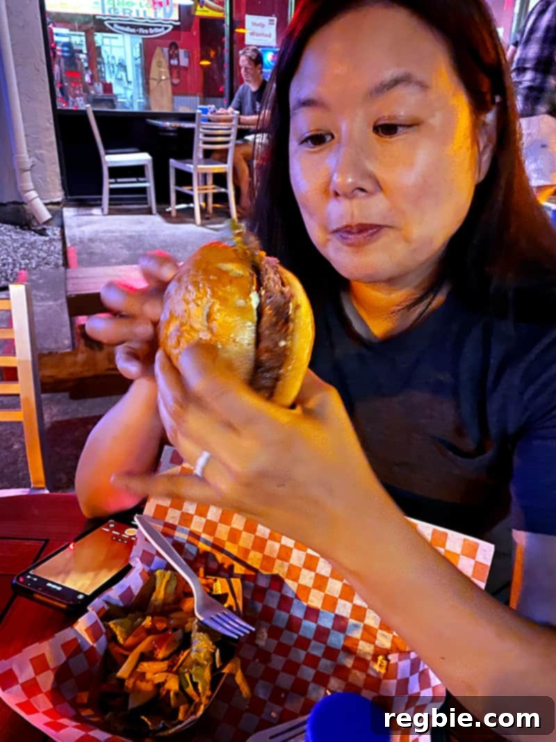 An Asian woman eating a gluten free burger from at Island Ono Loa Grill on the Big Island