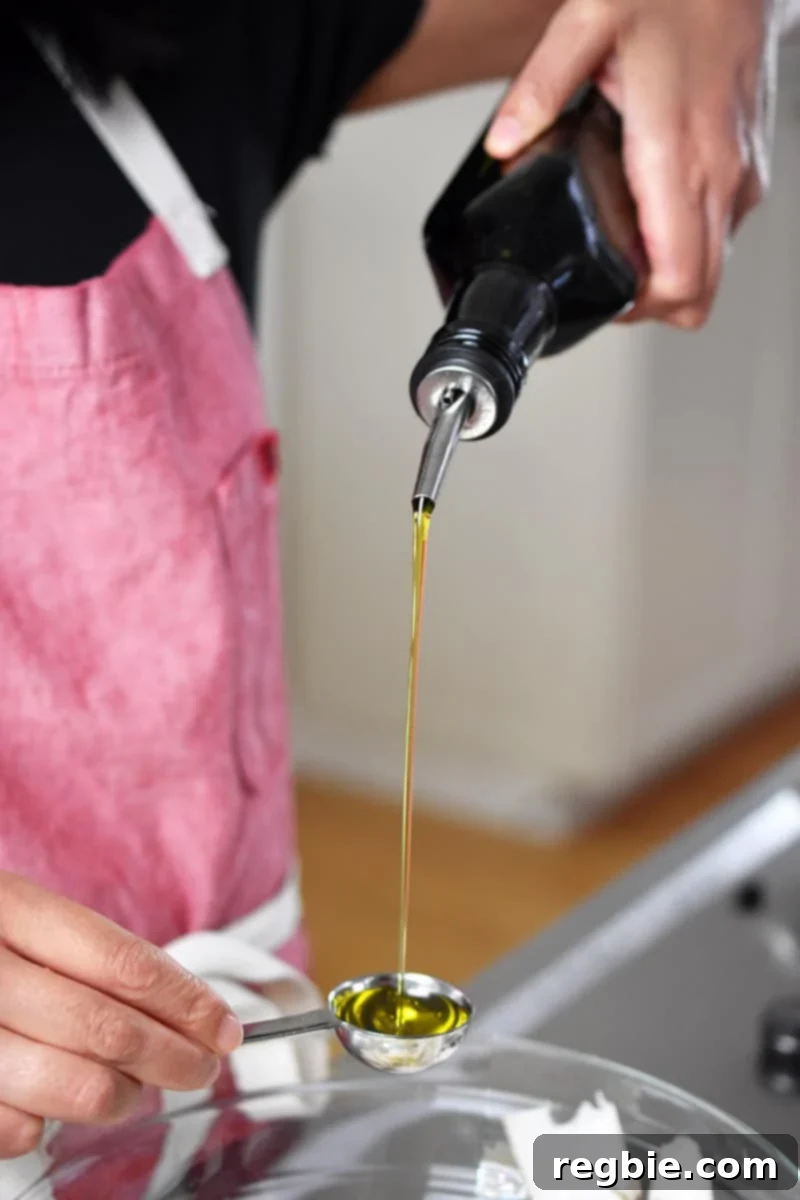 Pouring olive oil into a measuring spoon to add to king oyster mushroom salad