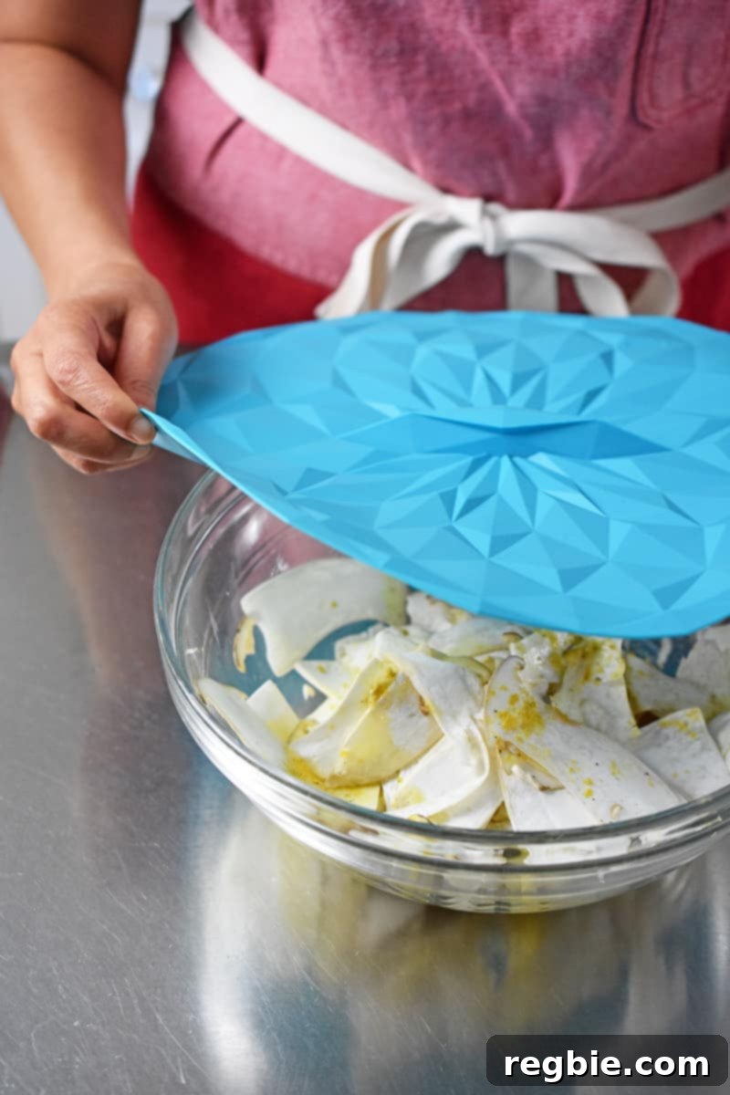 Covering a bowl of king oyster mushroom salad with a blue silicone lid.