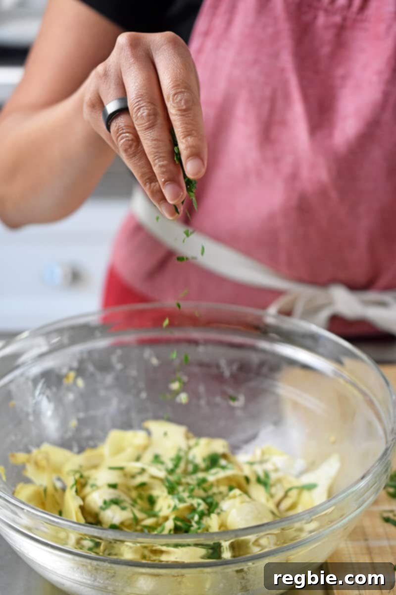 A person in a red apron is sprinkling fresh herbs on a bowl of mushroom salad
