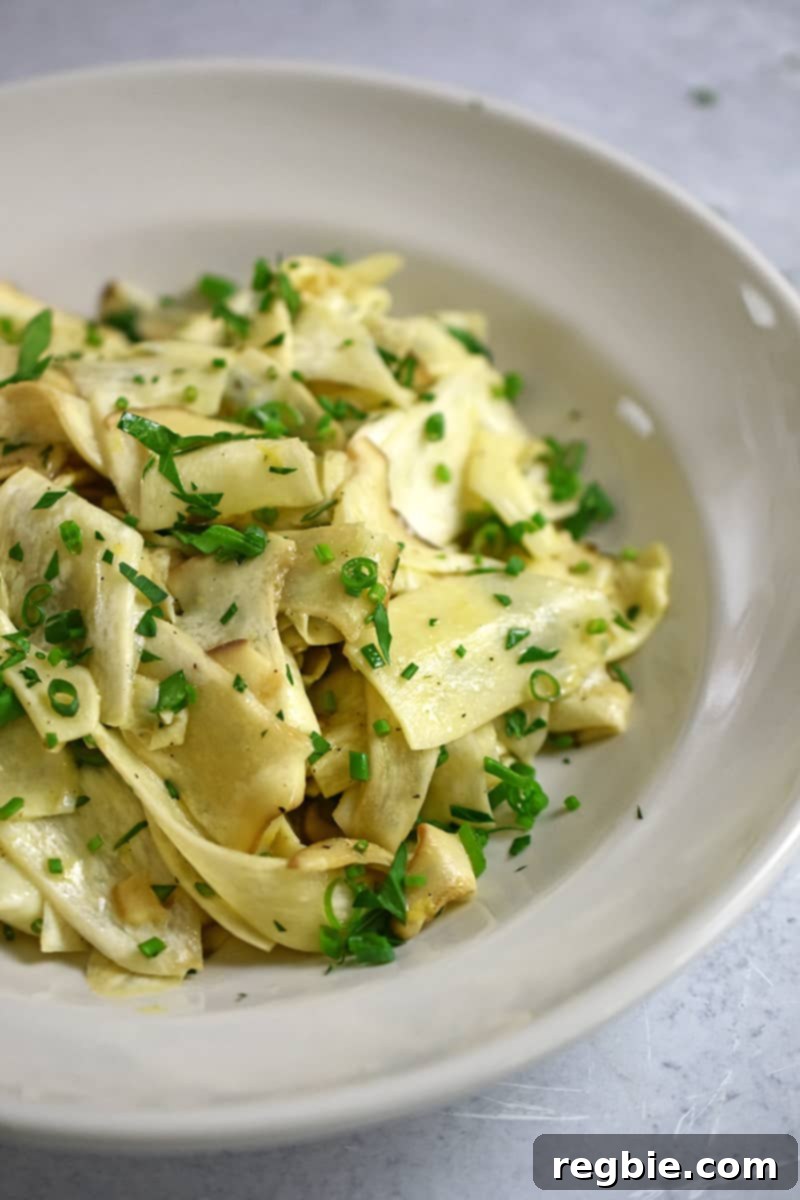 Closeup side angle of a bowl of King Oyster mushroom salad with lemon vinaigrette and fresh herbs
