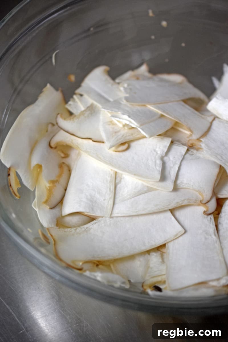Close up of thinly sliced king oyster mushrooms in a glass bowl.