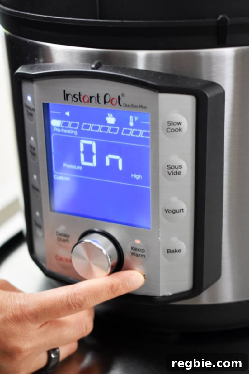 A finger pressing a button on the Instant Pot display to start cooking.