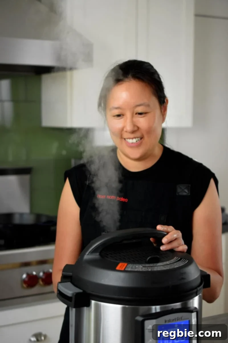 An Asian woman manually releasing steam from an Instant Pot after cooking.