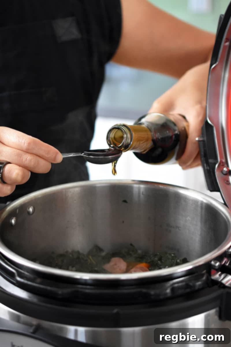 A person measuring out sherry vinegar to add to the finished Instant Pot soup.