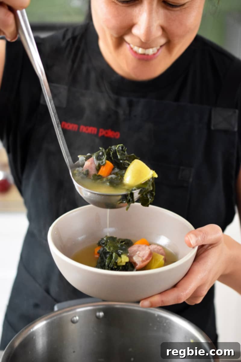A smiling Asian woman ladling Instant Pot kale and sausage soup into a bowl.