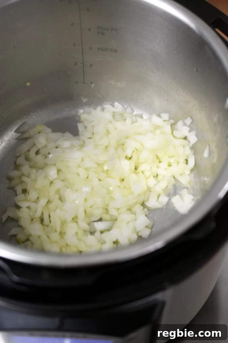 Diced onions being sautéed in an Instant Pot, turning translucent.