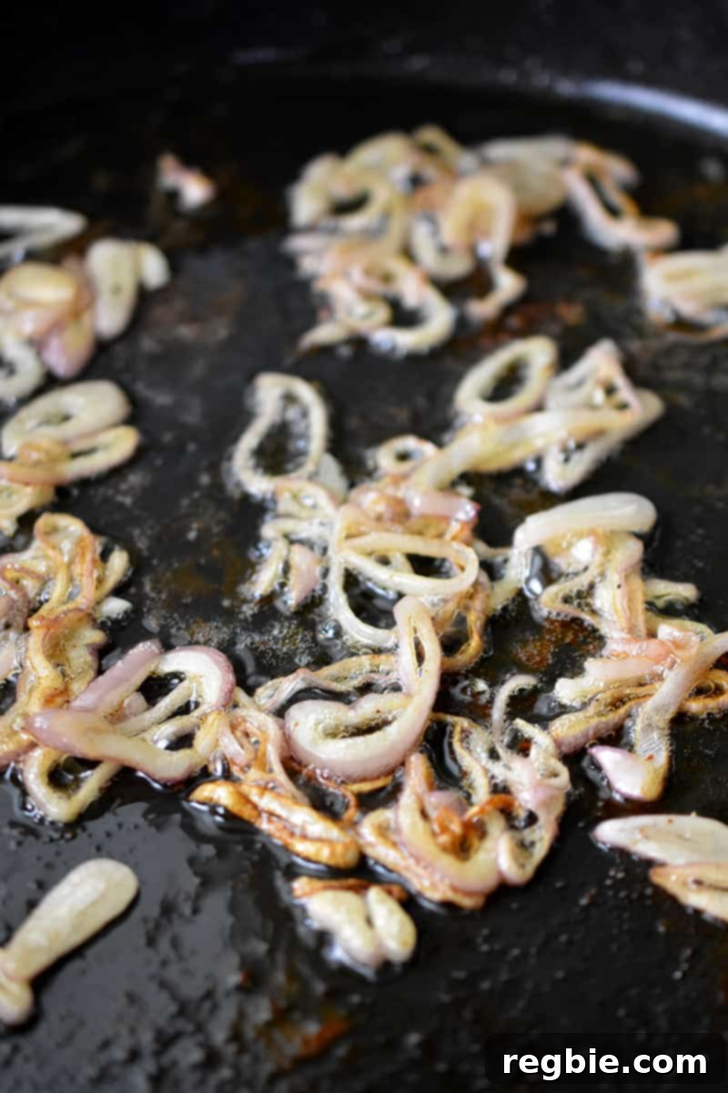 A closeup shot of tender and browned sliced shallots in a cast iron skillet