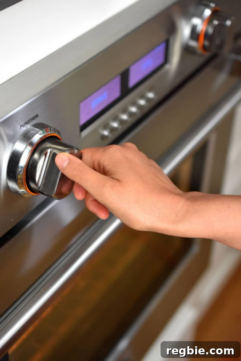Guilt Free Apple Crisp 13 A hand is turning the dial on a wall oven.