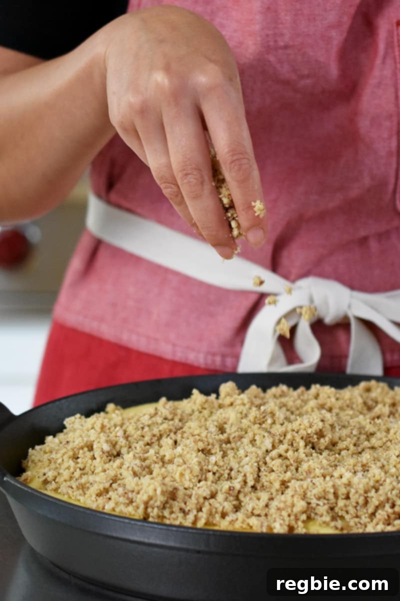 Guilt Free Apple Crisp 17 A hand is adding gluten-free, paleo topping onto an apple crisp.