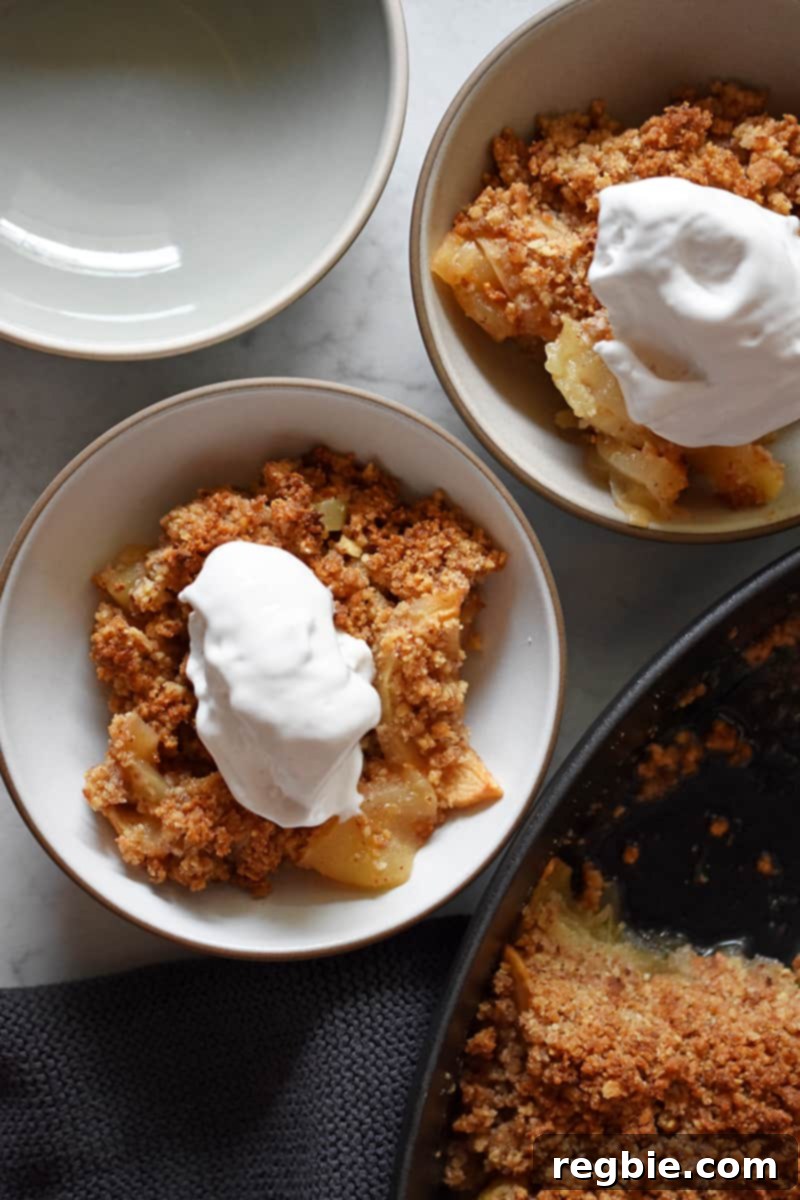 Guilt Free Apple Crisp 3 An overhead shot of two bowls of paleo, vegan, and gluten-free apple crisp topped with dollops of whipped coconut cream.
