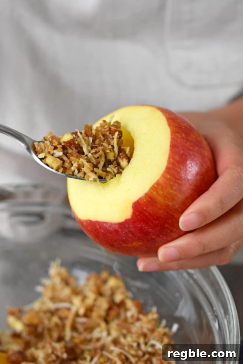 Wholesome Spiced Baked Apples 14 A spoon is filling a cored apple with a paleo and vegan sweet and salty filling.