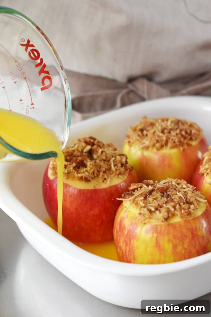 Wholesome Spiced Baked Apples 17 Pouring orange juice from a Pyrex measuring cup into a baking dish filled with stuffed apples